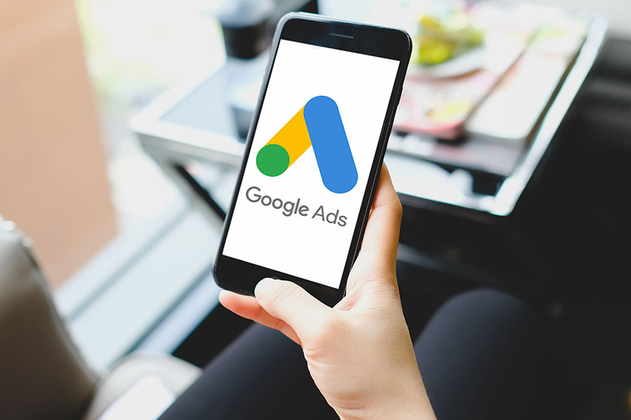 Mano che sostiene uno smartphone che visualizza il logo Google Ads