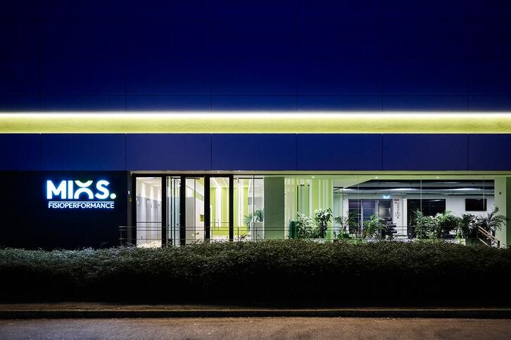 Scorcio notturno della sede Mios Fisioperformance con logo insegna, lunga vetrata