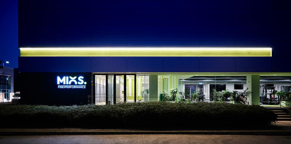 Scorcio notturno della sede Mios Fisioperformance con logo insegna, lunga vetrata